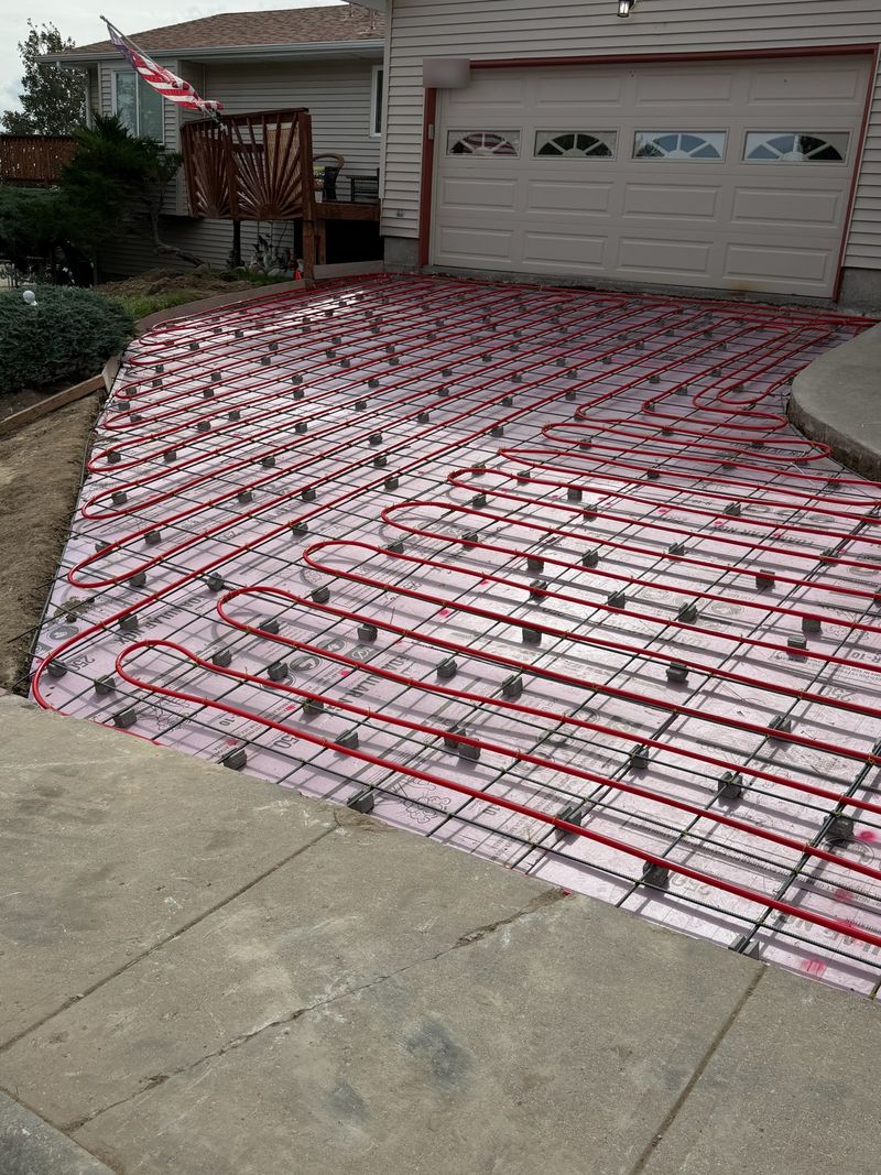 Close-up of red PEX radiant tubing tied to rebar over insulation board